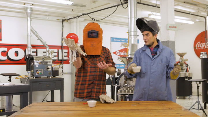 Two coffee roasters wearing protective gear are giving a demonstration on heat transfer