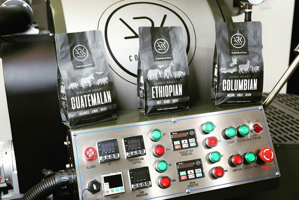 A roaster with bags of coffee sitting on the control panel for presentation.