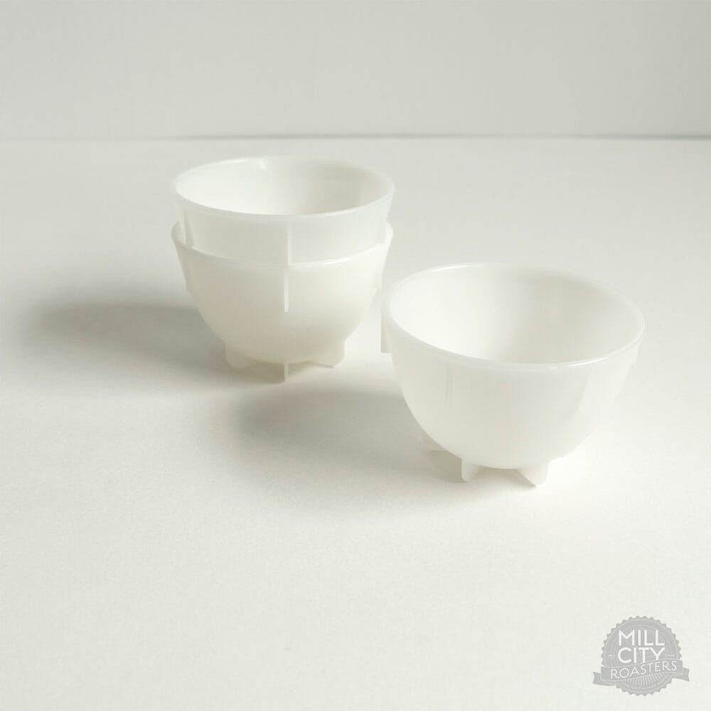 Against a white background, a few bowls sit in the center. Two of the bowls are stacked within each other and the last bowl sits by itself. The small bowls are casting a shadow to their left.