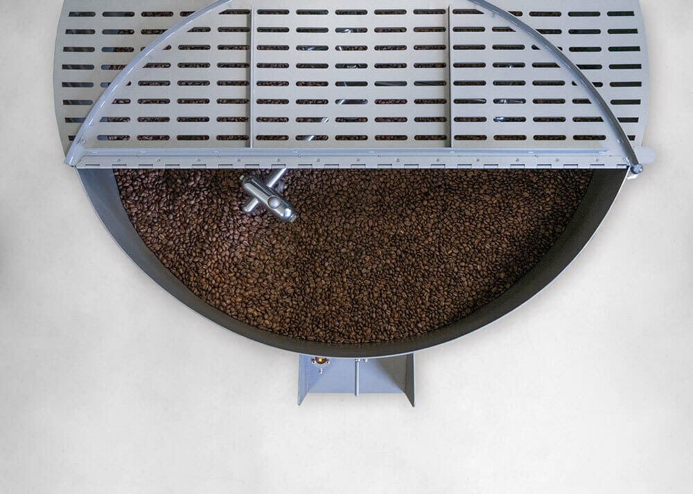 A cooling tray open filled with roasted coffee beans shot from an aerial view.
