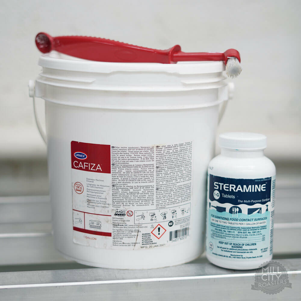 A big white bucket with a small red scoop and brush.