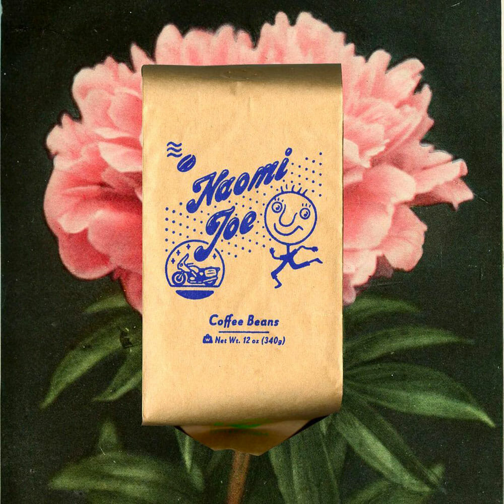 A kraft coffee bag in front of a flower.